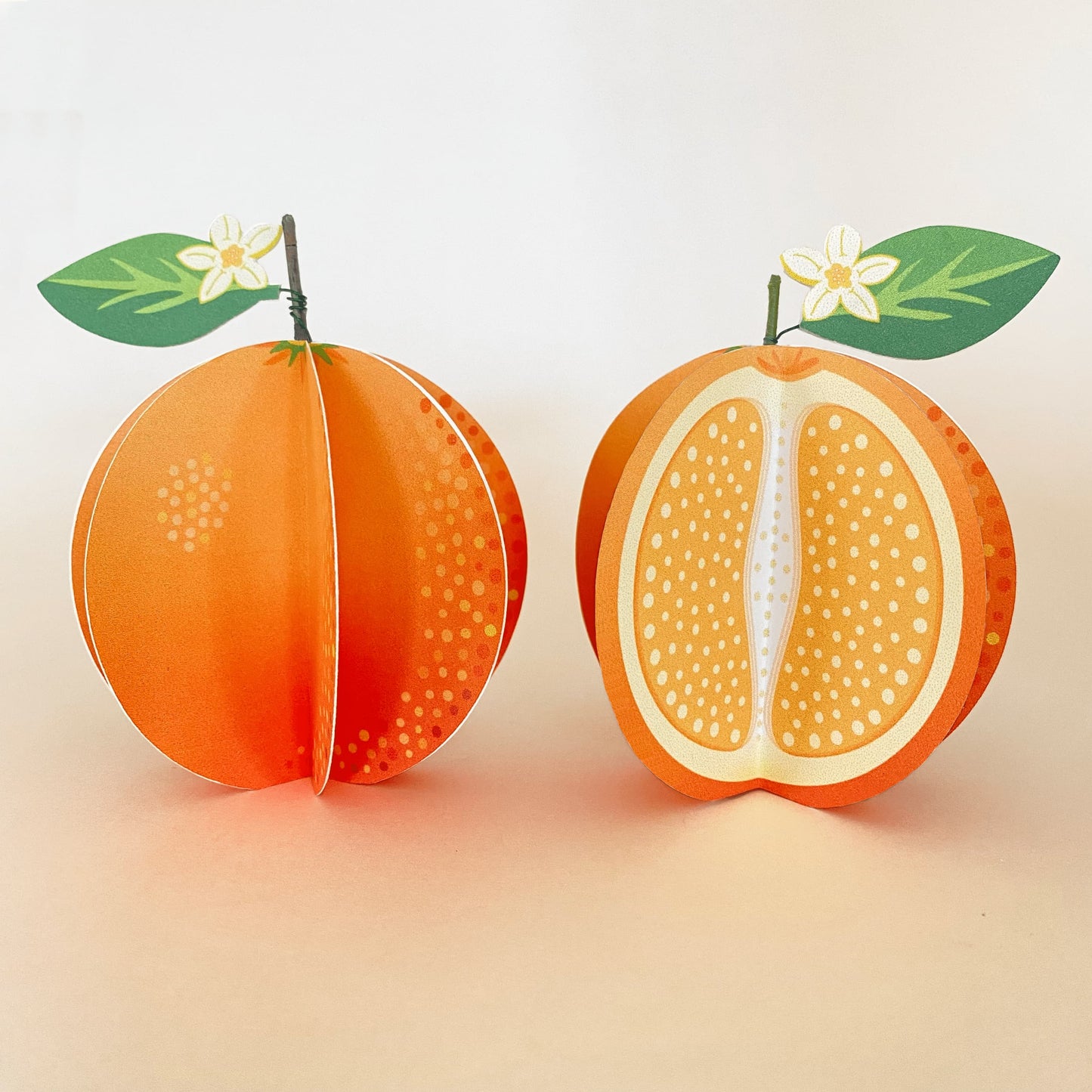 a set of 2 handmade paper oranges, one whole and one cut