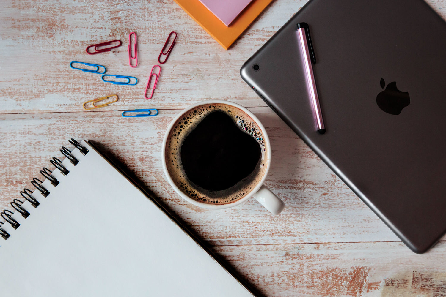 image of a desk with a cup of coffee, a notebook and an ipad