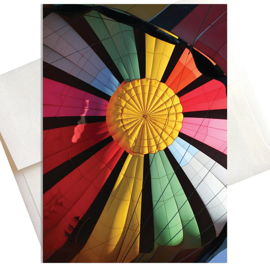A photo of a colorful hot air balloon in the process of being inflated before a flight. The vibrant fabric of the balloon stretches out, showcasing a beautiful rainbow pattern.