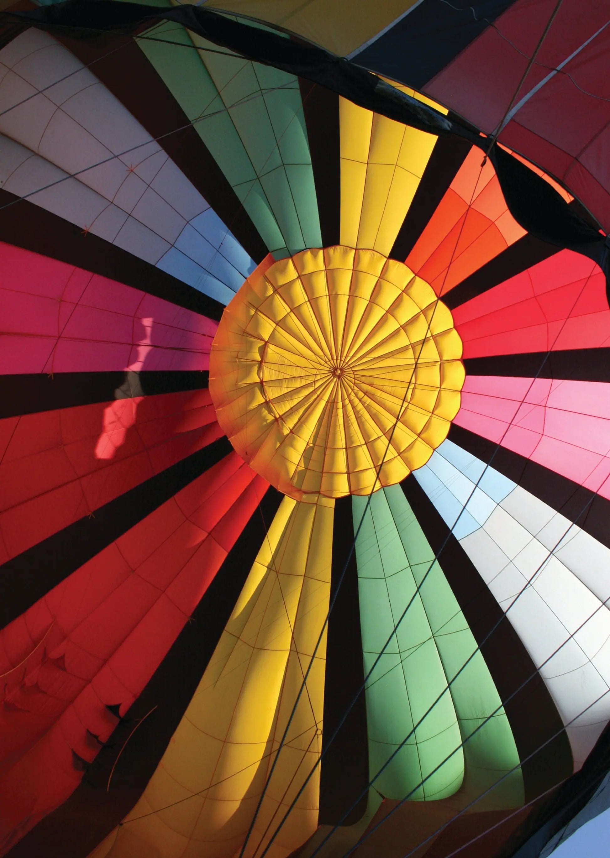 A photo of a colorful hot air balloon in the process of being inflated before a flight. The vibrant fabric of the balloon stretches out, showcasing a beautiful rainbow pattern.