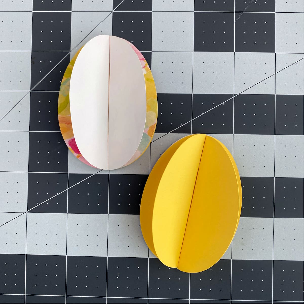 two halves of a paper egg on a grid background