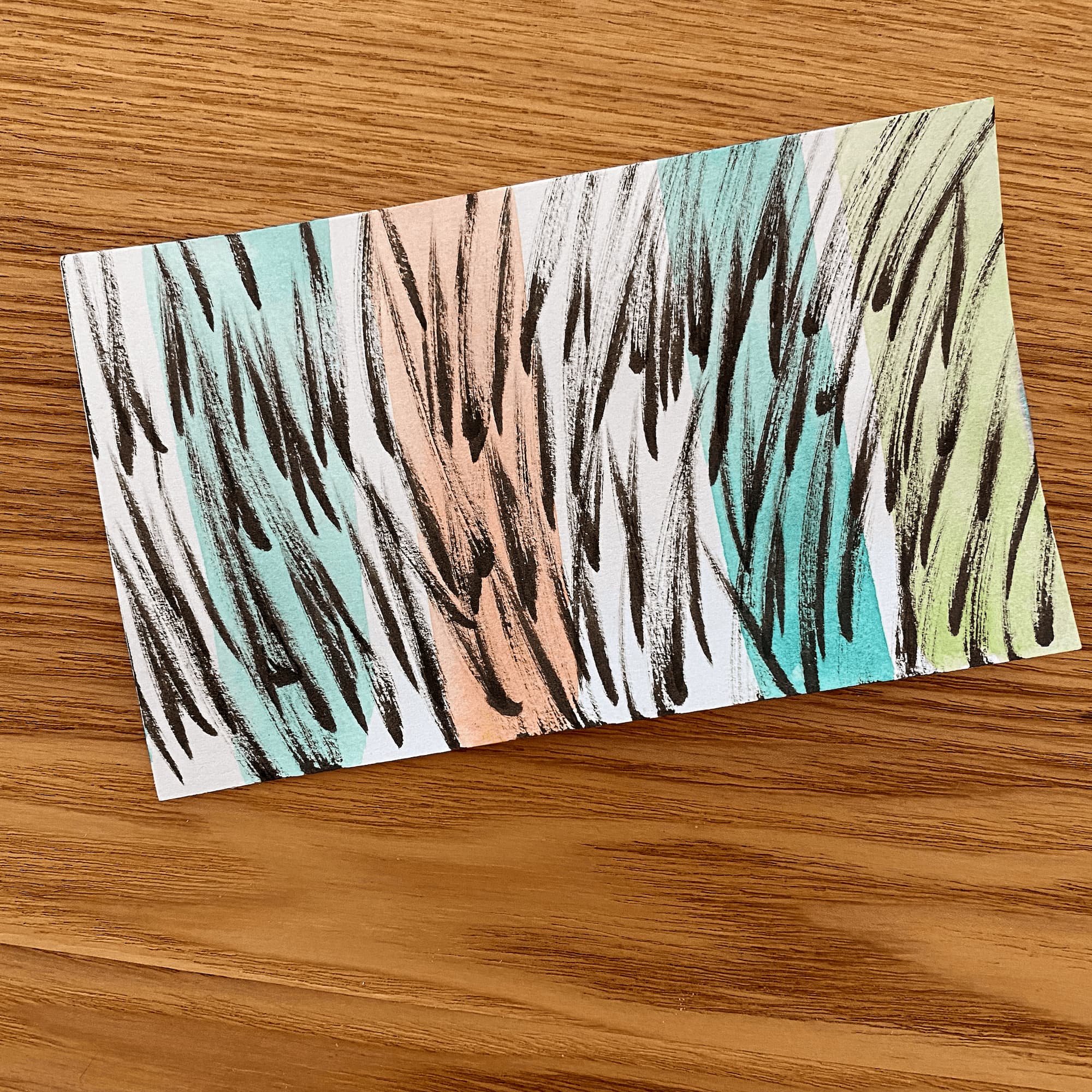 drawing on index card made with short strokes in black ink and thick watercolor stripes in turquoise, peach and light green.
