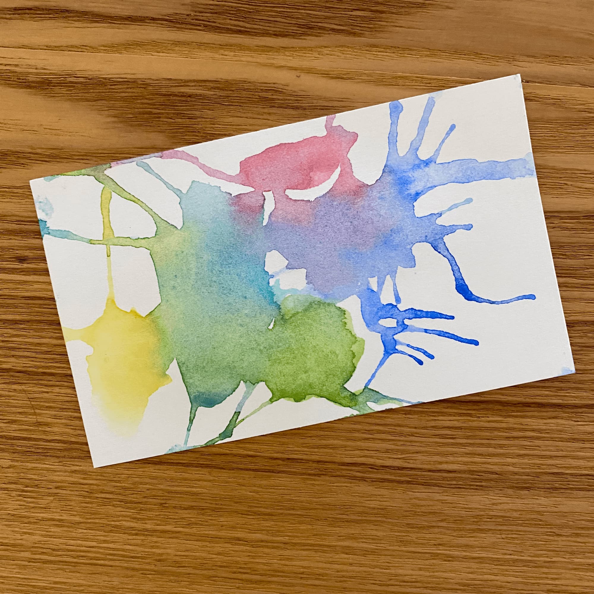abstract watercolor done with lotches of yellow, green, turquoise, red and blue on an index card
