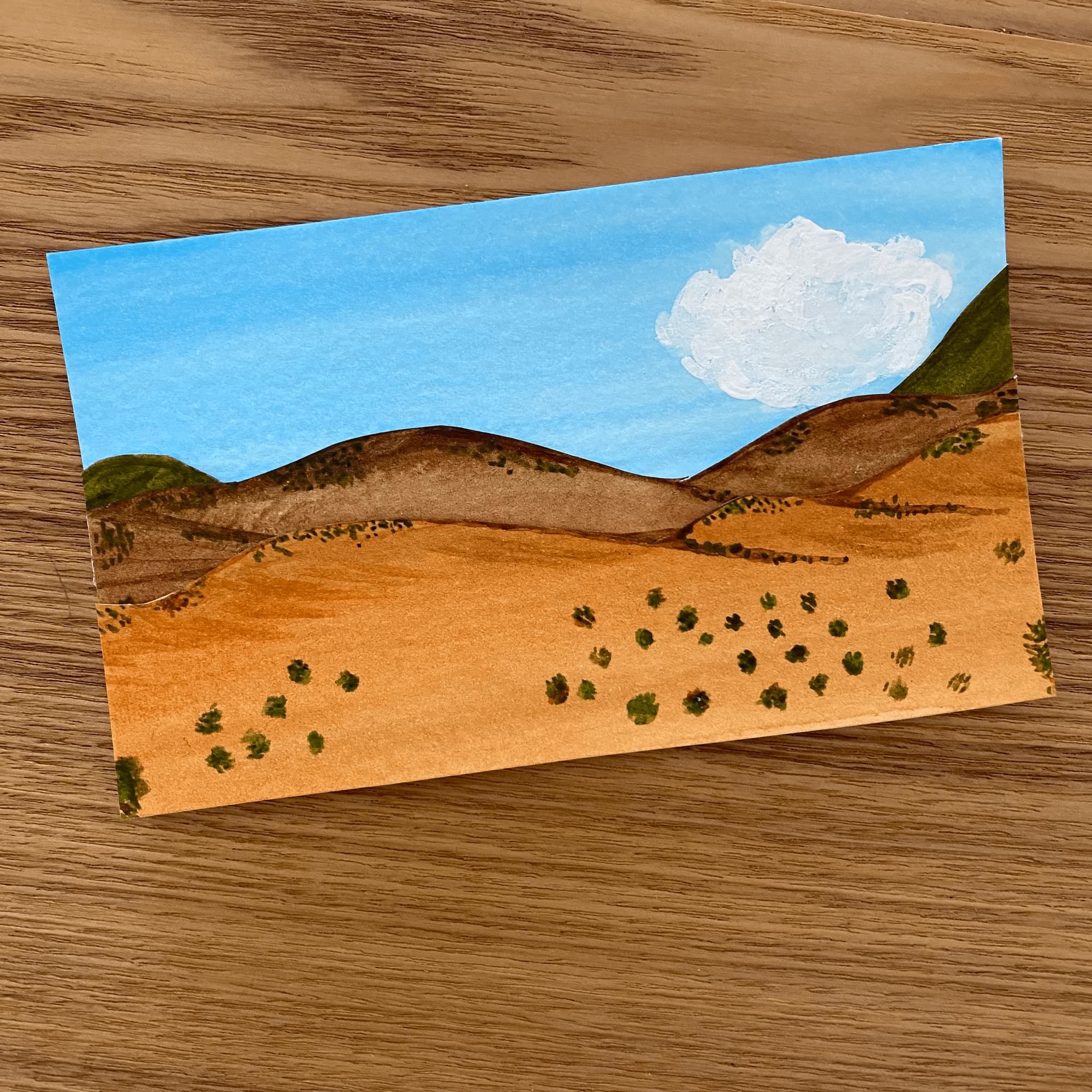 Collage of chaparral hills against a blue sky, done with watercolors and gouache.