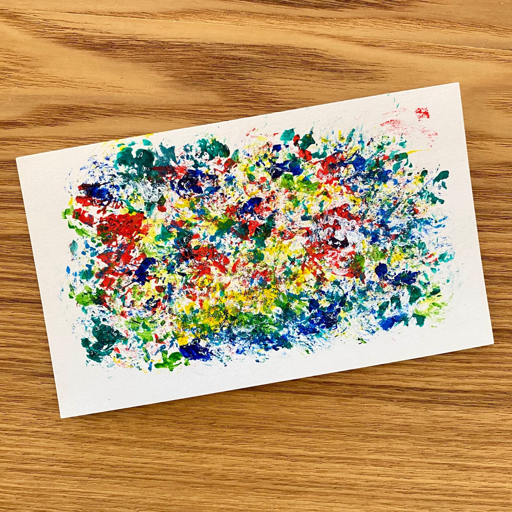 abstract painting on an index card of multicolored paint daubs made with acrylic paints.