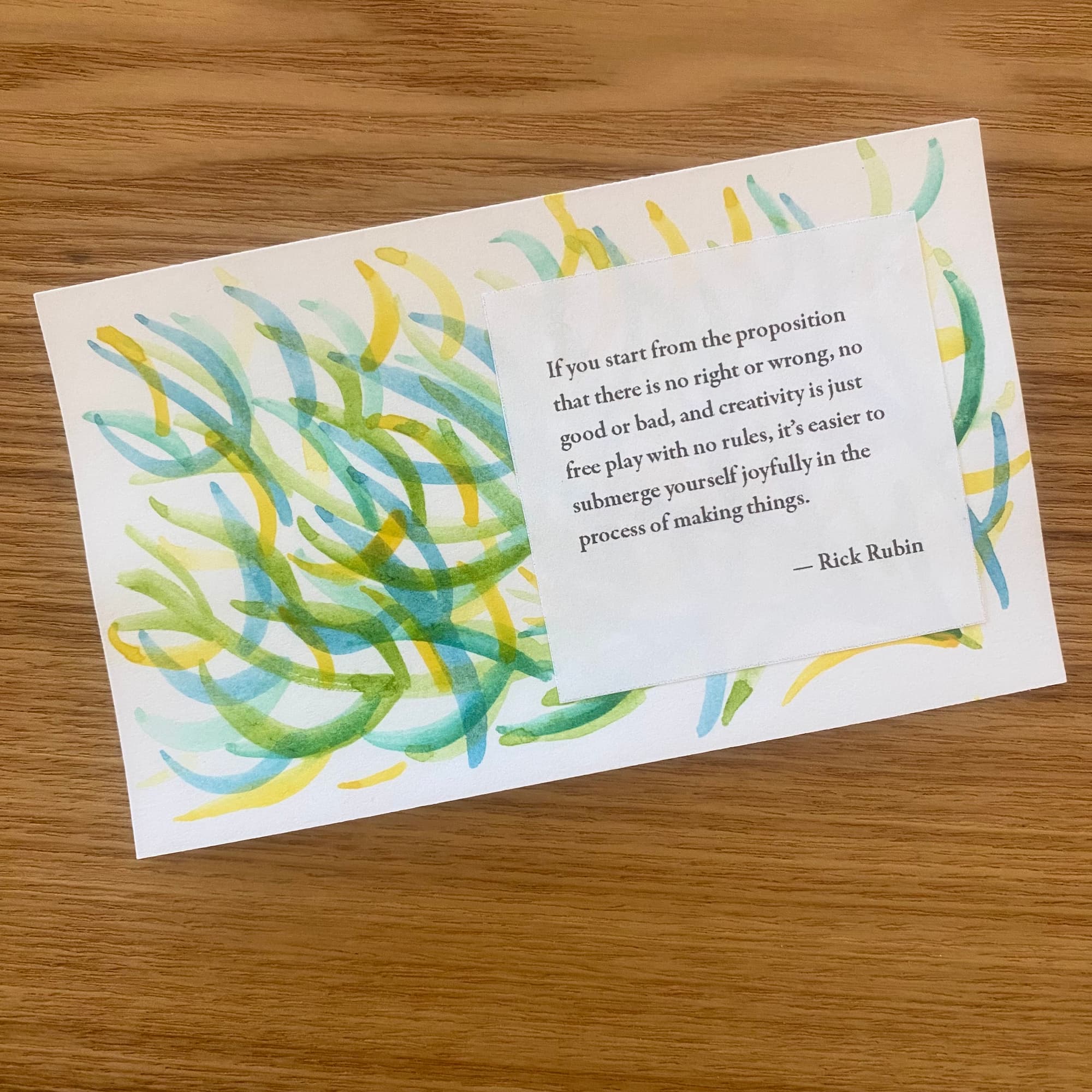 abstract watercolor strokes in green, yellow and turquoise with a printed insporational statement from Rick Rubin about approaching art with no right or wrong and doing it as free play
