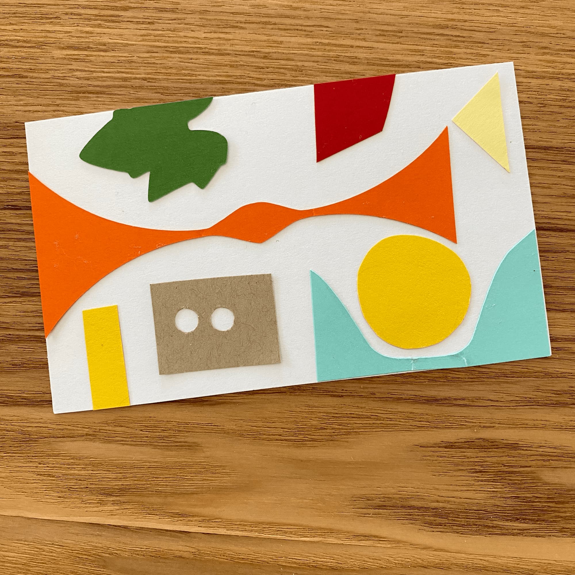 collage on index card made with paper in shades of yellow, red, turquoise, dark green and kraft brown.