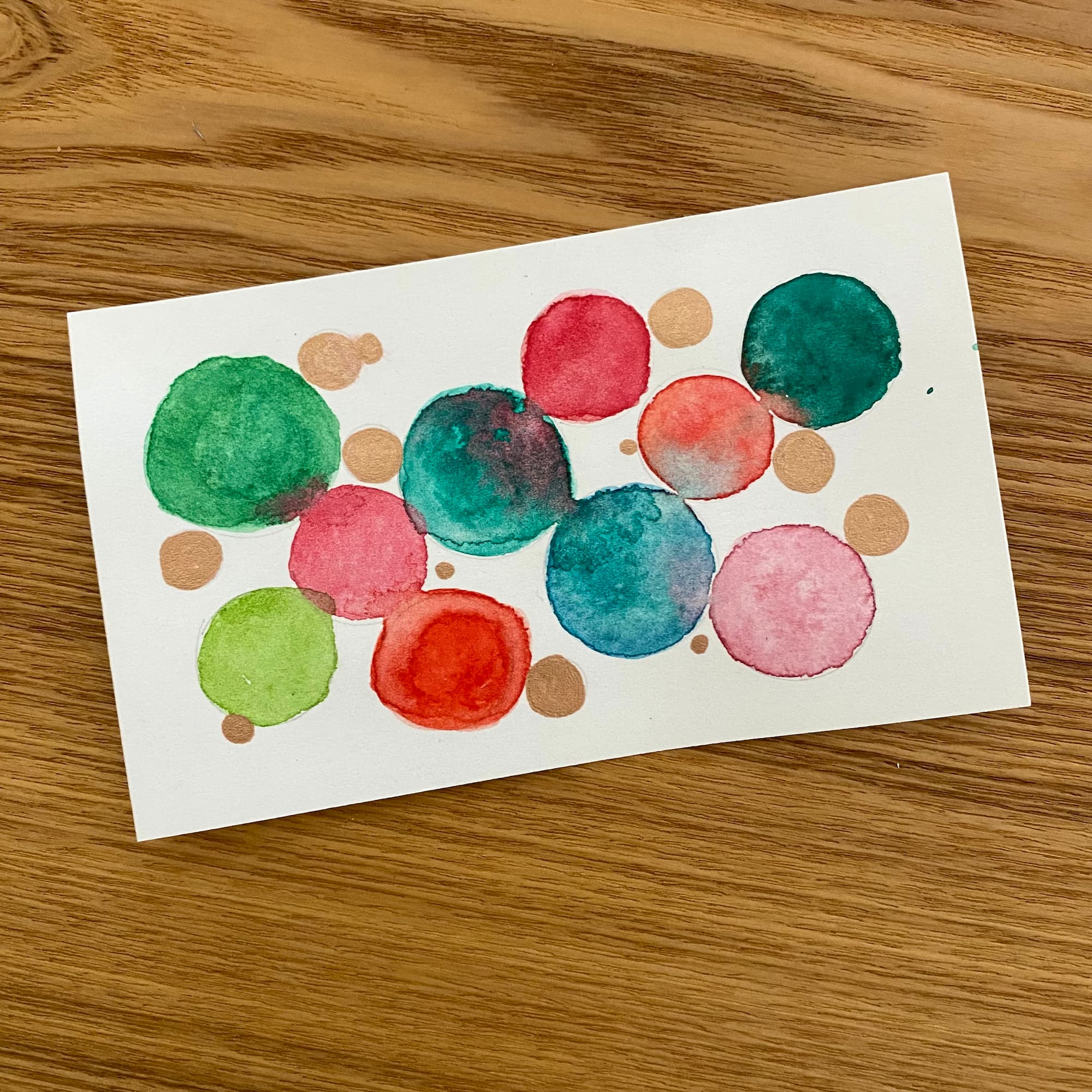 abstract watercolor of various circles in shades of red, green and metallic bronze