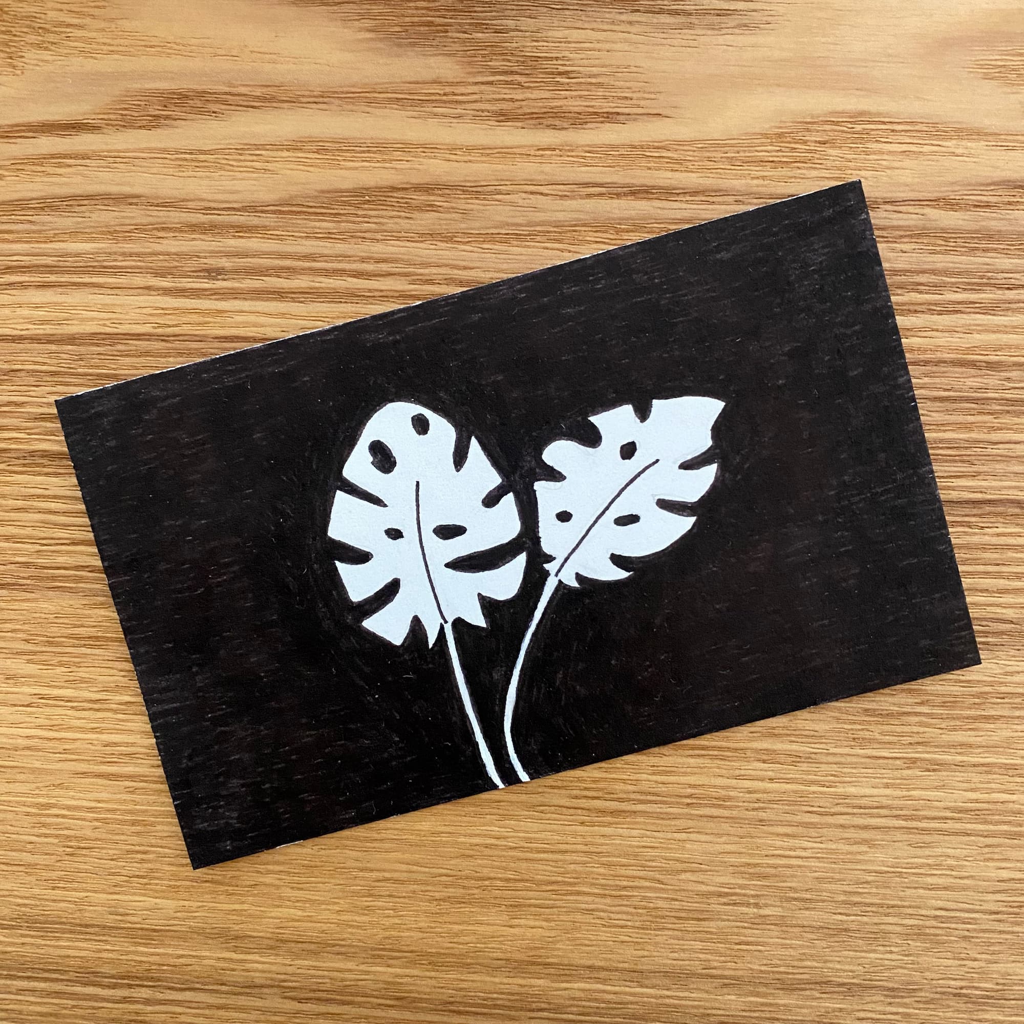 reverse image of two monstera leaves done in black ink