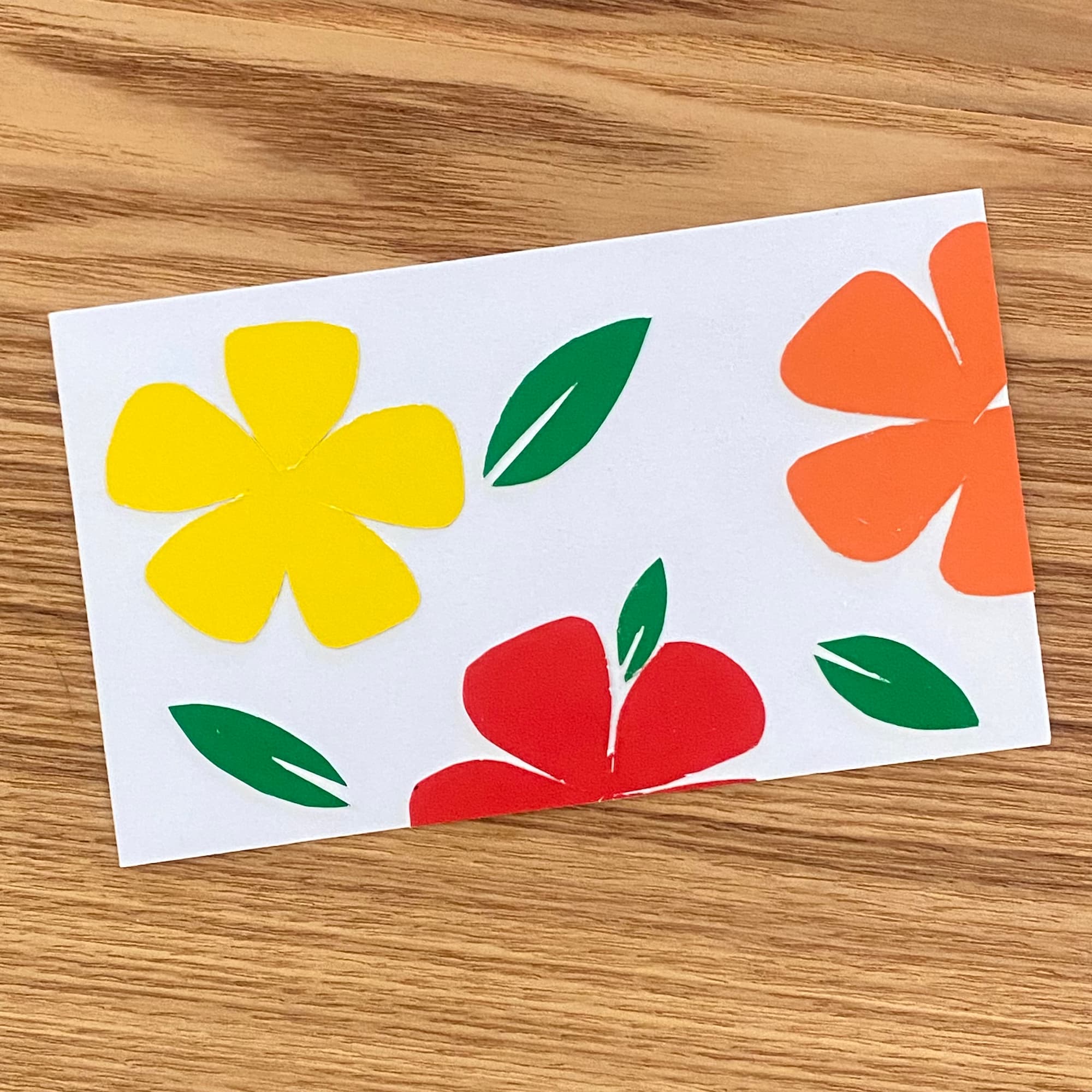 collage of simple flower shapes and leaves in yellow, orange and red paper
