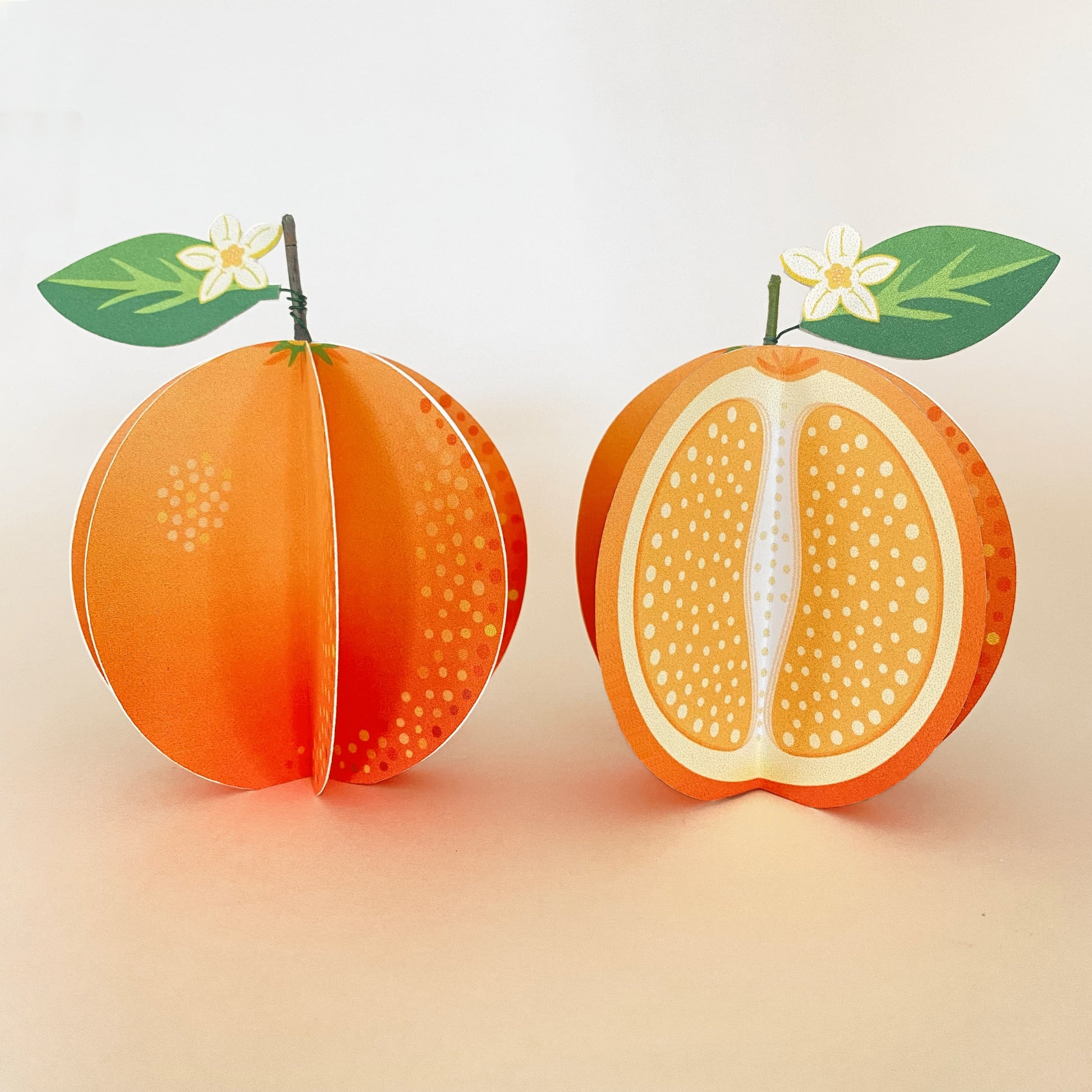 a set of 2 handmade paper oranges, one whole and one cut