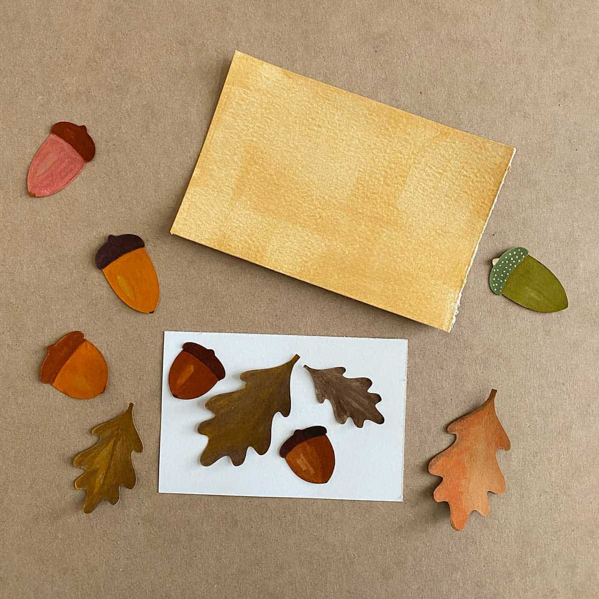 Paper acorns and leaves on a brown background featured in Cakewalk DIY Paper Craft tutorial.
