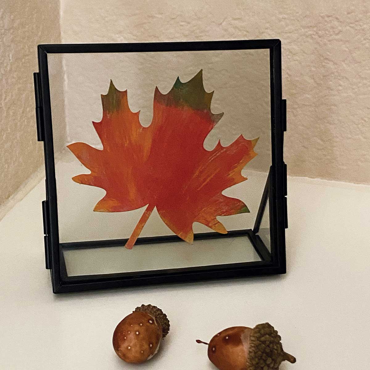 Framed red maple leaf on a white surface with acorns for Cakewalk DIY Paper Craft tutorial.