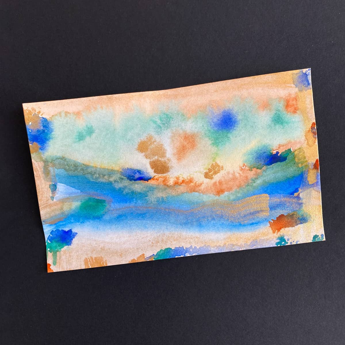 Index card with an abstract watercolor painting with a blue, green, brown and gold paint on a black background by Mozaic Studio for ICAD 2025