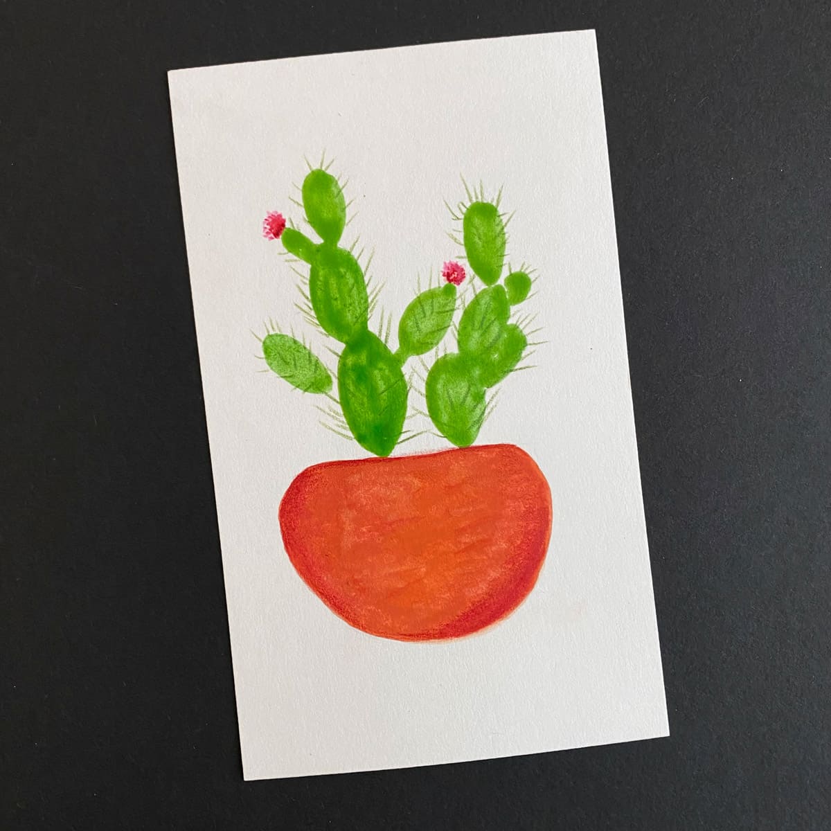 Index card with a gouache painting of a cactus in a terracotta planter on black background by Mozaic Studio for ICAD 2025