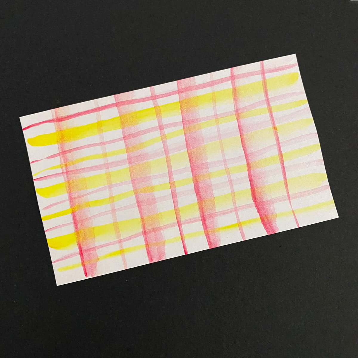 Index card with a watercolor plaid in pink and yellow on a black background by Mozaic Studio for ICAD 2025