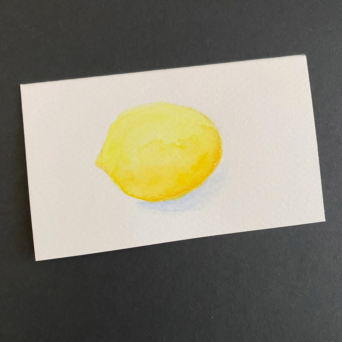 Index card with a lemon painted in watercolors on a black background by Mozaic Studio for ICAD 2025