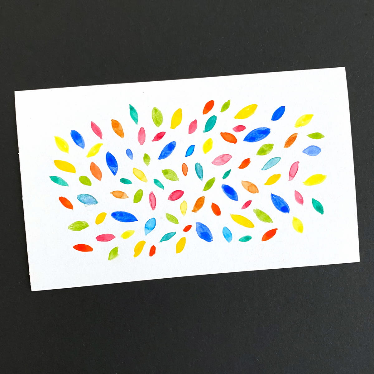 Index card with an abstract design of multicolor leaf shapes done in watercolor  on a black background by Mozaic Studio for ICAD 2025