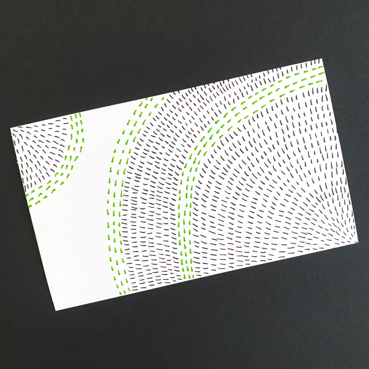 Index card with an abstract design of ink marks in black and green on a black background by Mozaic Studio for ICAD 2025