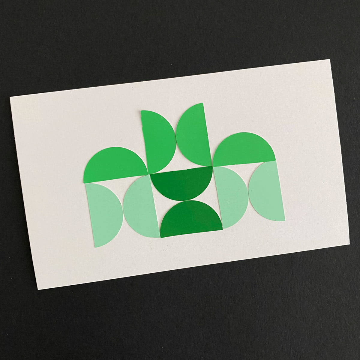 Index card with a paper collage of green half-circle shapes on a black background by Mozaic Studio for ICAD 2025