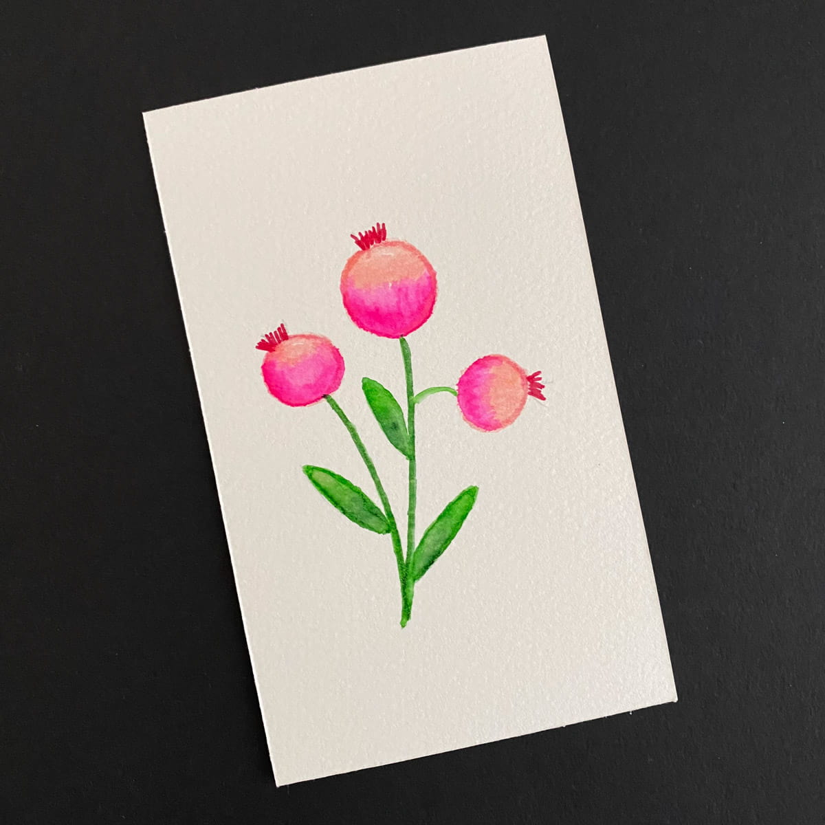 Index card with a watercolor painting of pink flowers on a black background by Mozaic Studio for ICAD 2025