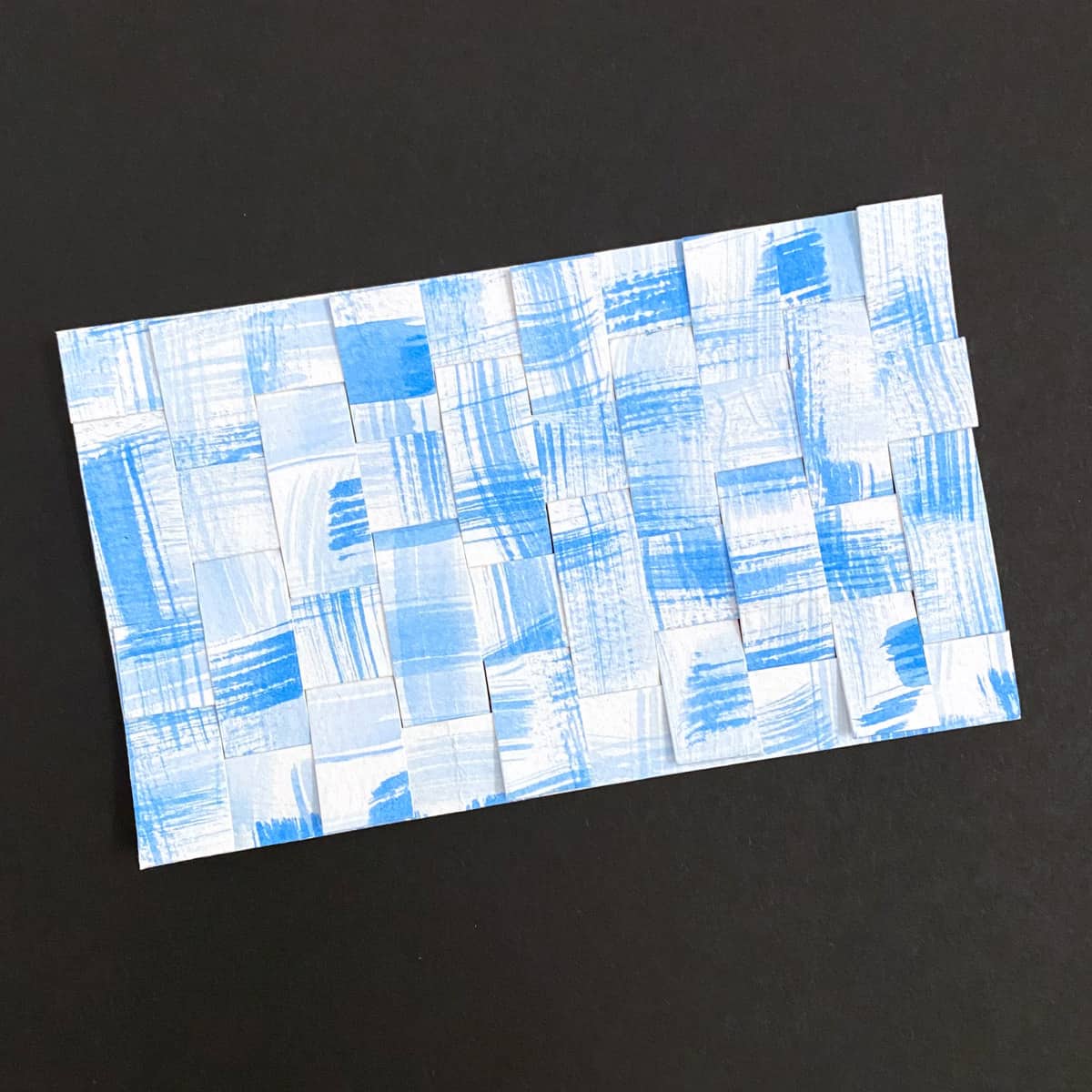 Index card with paper weave made with blue watercolors on a black background by Mozaic Studio for ICAD 2025.