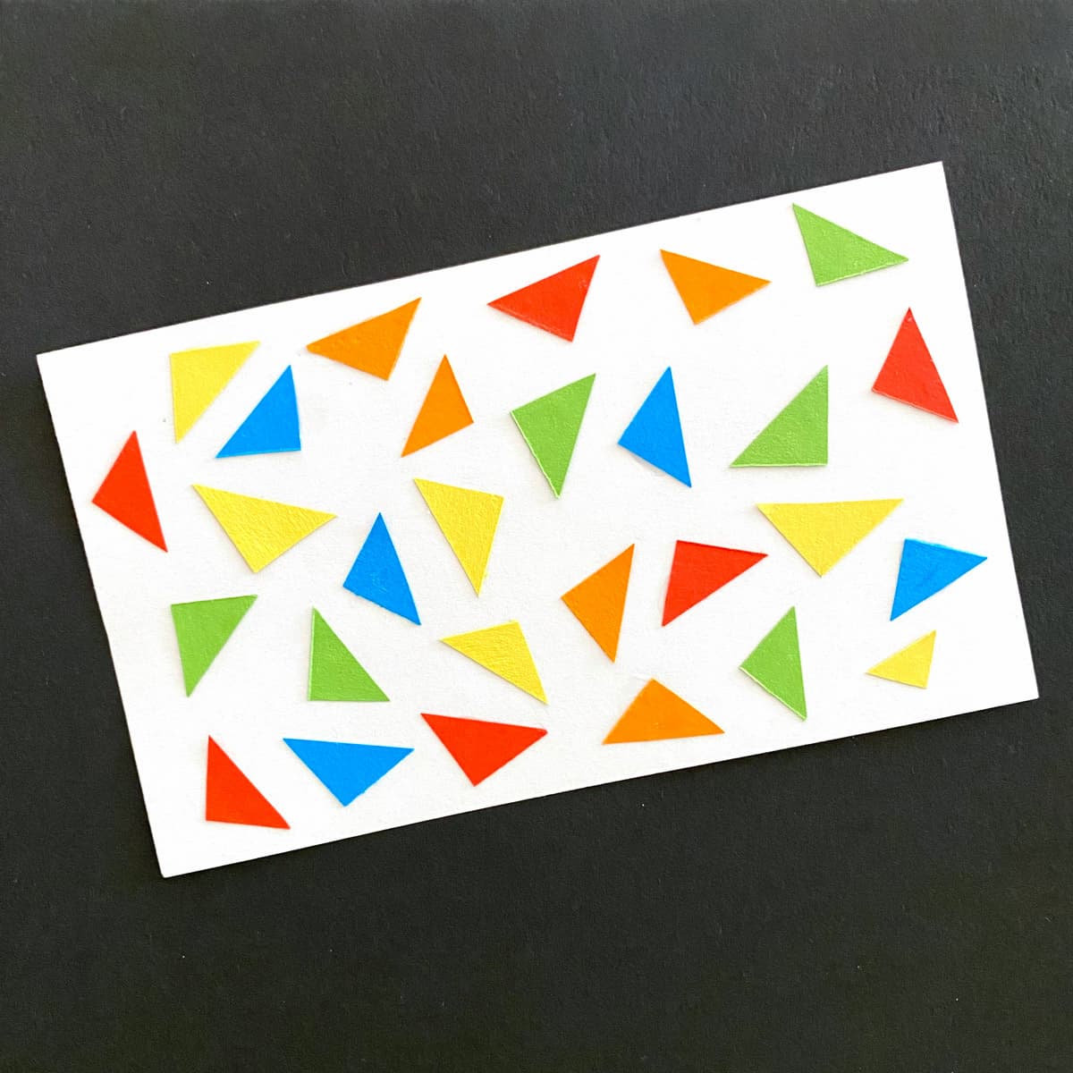 Index card with paper triangels in red, blue, green, orange and yellow on a black background by Mozaic Studio for ICAD 2025.