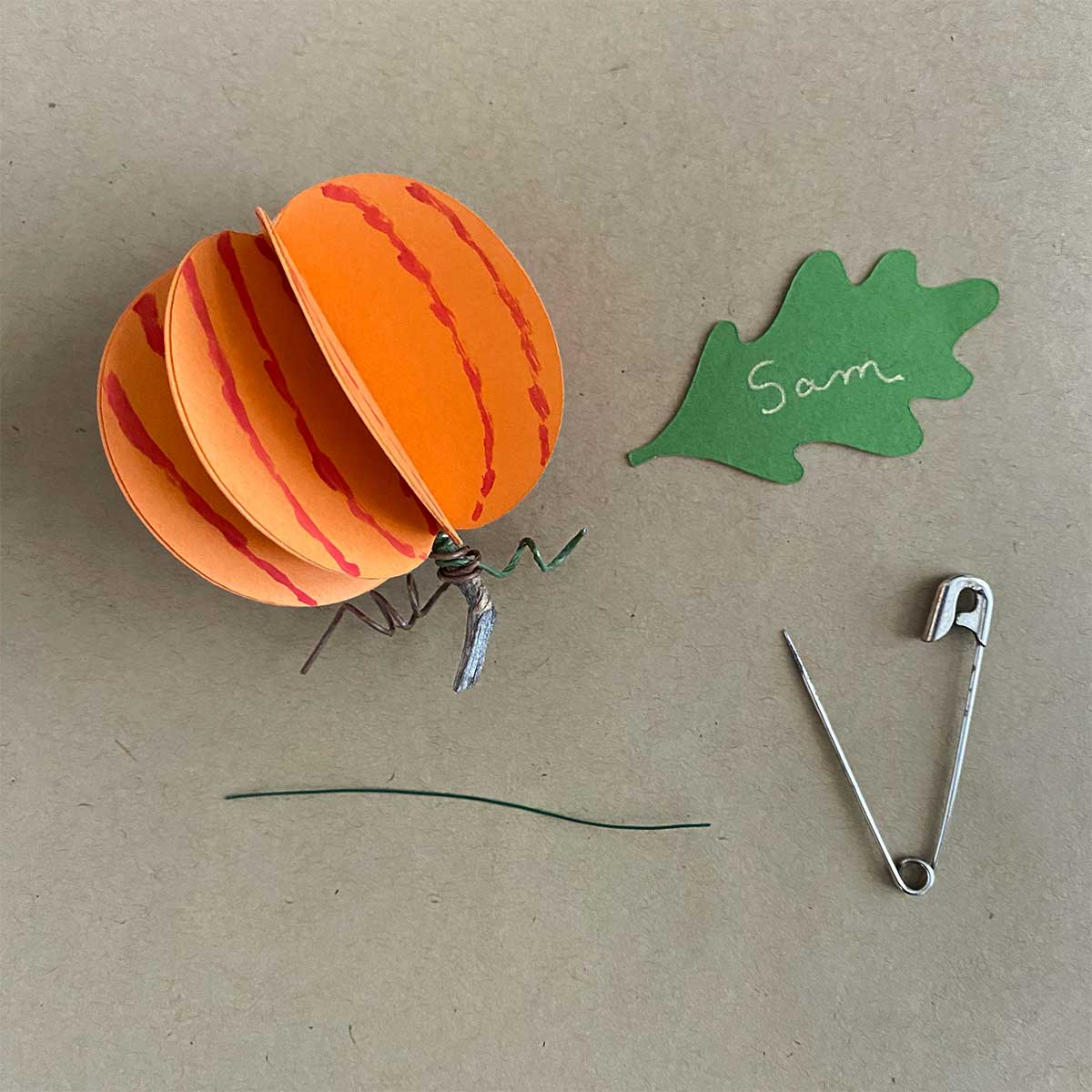 Paper pumpkin, paper oak leaf, safety pin and floral wire for a Cakewalk DIY Paper Craft tutorial. 