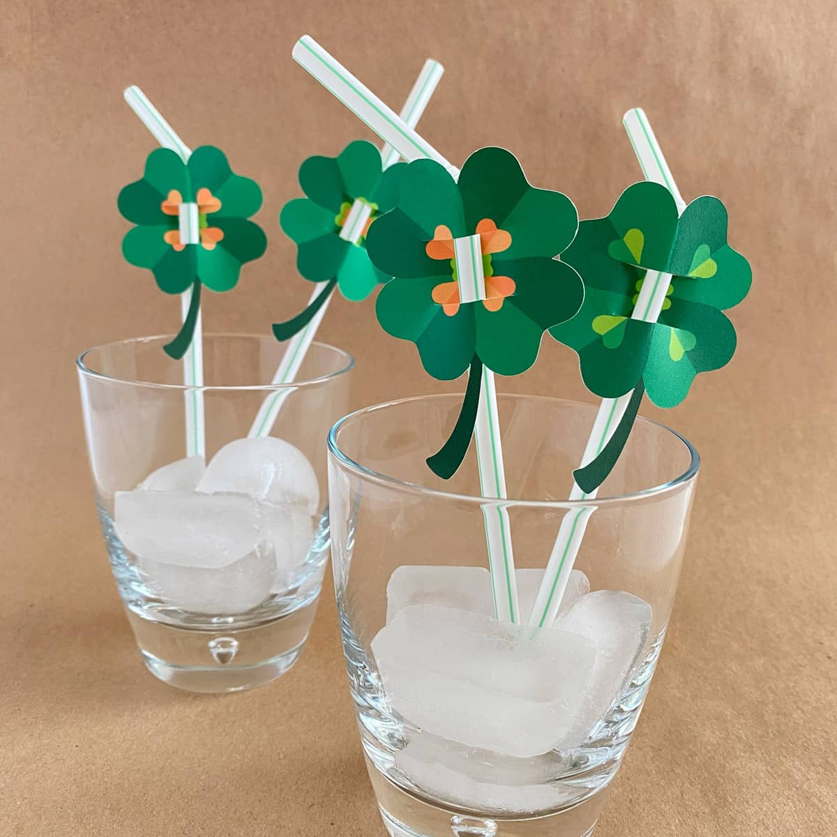 St. Patrick’s Day Shamrock Toppers Printable with two toppers in a glass of ice by Make It Cakewalk