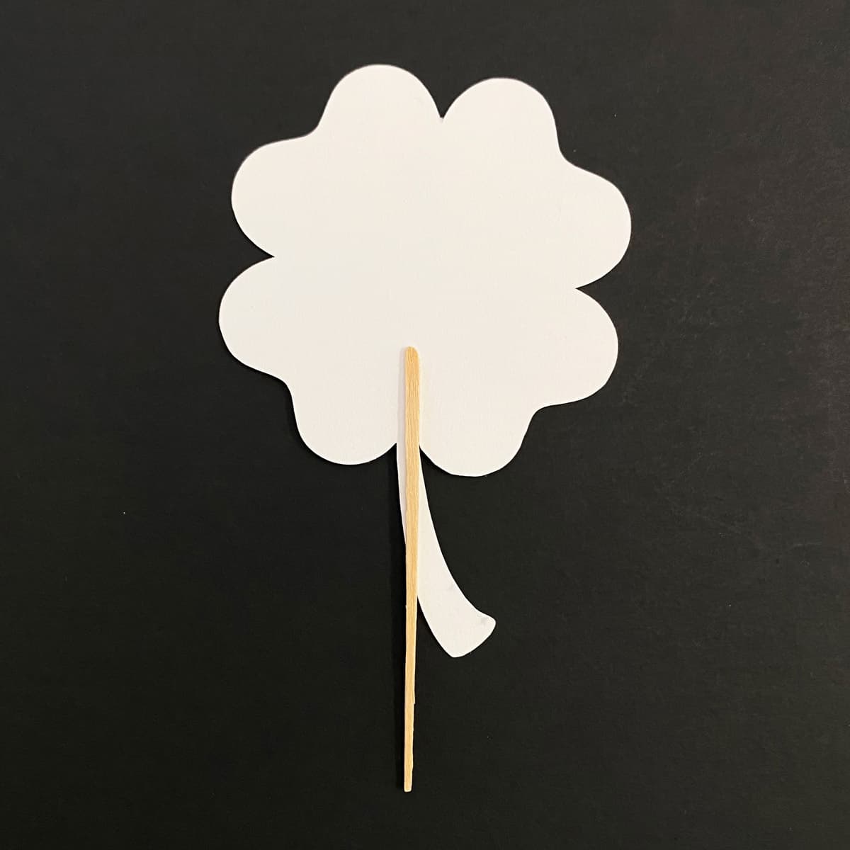 Back of a paper shamrock shown with a toothpick attached